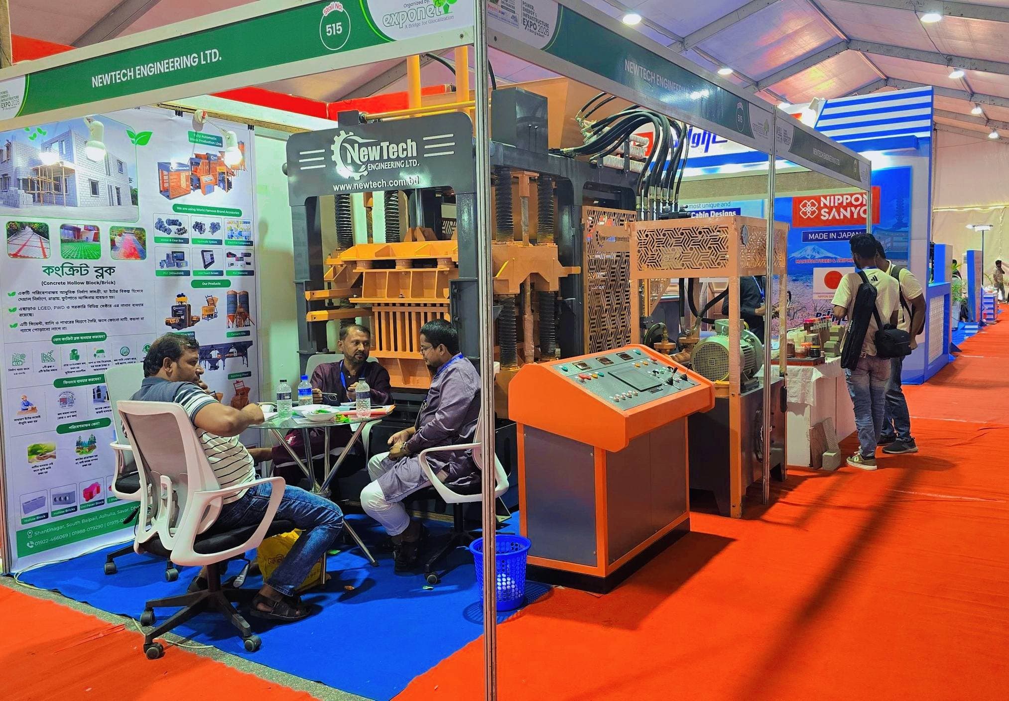 Visitors at the NewTech Engineering booth discussing block machine specifications